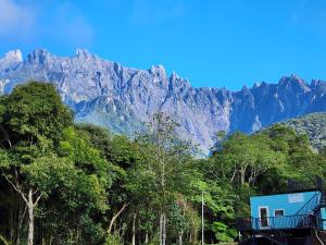 a blue house in front of a mountain at The Mountain Camp at Mesilau, Kundasang by PrimaStay in Ranau