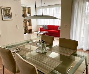 uma sala de jantar com uma mesa de vidro e um sofá vermelho em Tertianum Parkresidenz Meilen em Meilen