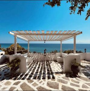 a pergola with a table and chairs on the beach at Villa Olga studios in Nea Skioni