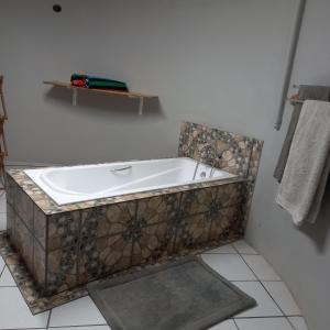 a bath tub in a bathroom with a tile floor at Rilli's Inn Studio in Mtunzini