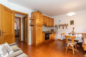 eine Küche mit Holzschränken und einem Tisch in einem Zimmer in der Unterkunft Ciesa Migon in Alleghe + 7 Fotos