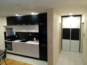 una cocina con armarios blancos y electrodomésticos negros en Tina en Užice