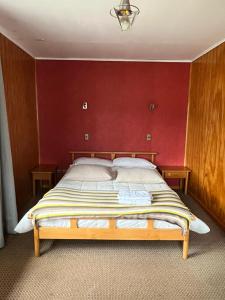 sypialnia z dużym łóżkiem z czerwoną ścianą w obiekcie Hospedaje BoppHouse w mieście Coihaique