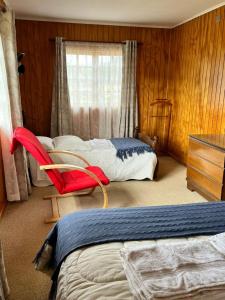 a bedroom with a bed and a red chair in it at Hospedaje BoppHouse in Coihaique
