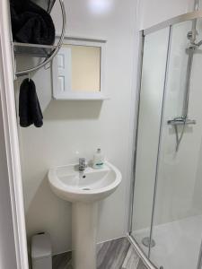 a white bathroom with a sink and a shower at RUDGRAVE SQUARE WALLASEY in Wallasey
