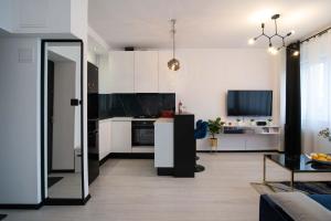 a kitchen with white cabinets and a living room at Glamour Apartment - w sercu miasta obok rynku, klimatyzacja, możliwy parking gratis in Katowice