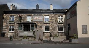 an old stone building with a sign in front of it at Hope and Anchor in Flookburgh