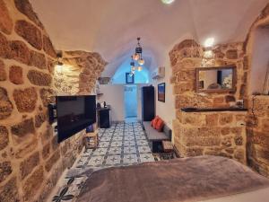 a room with a stone wall with a tv and a bed at Shafika house in ‘Akko
