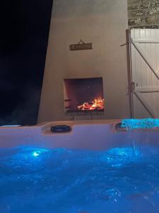 a hot tub with a fireplace in a room at le coin des hirondelles in Pontorson