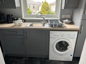 a kitchen with a sink and a washing machine at Mustard Seed 43 Seamore Street 1/L Largs in Largs