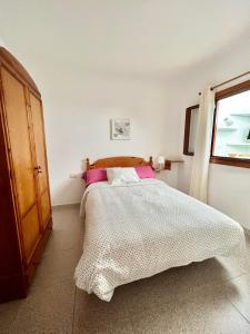 Un dormitorio con una cama con almohadas rosas y una ventana en Casa Los Jameos en Punta de Mujeres