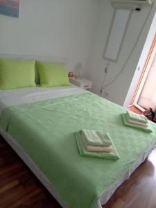 a bed with green sheets and two towels on it at Apartman Maksimović in Banja Koviljača