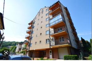 a tall apartment building with a car parked in front of it at Apartman Maksimović in Banja Koviljača