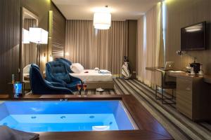 um quarto de hotel com uma banheira e uma cama em Retamares Suites & Golf - a sólo 30 mn de Madrid - Vistas a los lagos y Montaña - Ven a descansar !! 