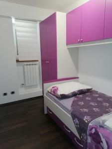 een kleine slaapkamer met paarse kasten en een bed bij Apartment Ena in Kukuljanovo