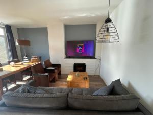 een woonkamer met een bank en een tv aan de muur bij Appartement Arnhem in Arnhem