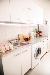 a white kitchen with a sink and a washing machine at Apartman Stella in Bosanska Gradiška
