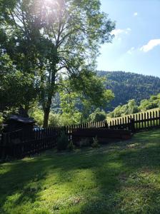 a wooden fence in a field with a tree at Chata Evka in Ružomberok