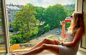 een vrouw in een raam die een glas wijn drinkt bij Double King Size Sunny Suite In Castle Area in Praag +35 foto's