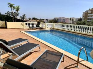 a swimming pool with two lounge chairs next to it at Villa Hermano with views and private pool in Lagos