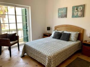 a bedroom with a bed and a chair and a window at Villa Hermano with views and private pool in Lagos +26 photos