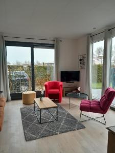 a living room with red chairs and a tv at Luxe 5 persoons bungalow op rustig vakantiepark nabij Leeuwarden in Dronrijp