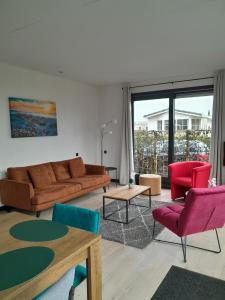 een woonkamer met een bank, stoelen en een tafel bij Luxe 5 persoons bungalow op rustig vakantiepark nabij Leeuwarden in Dronrijp