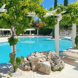 een zwembad met een boom en een rots bij All`Ombra del Carrubo in Polignano a Mare