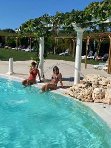 Dos mujeres están sentadas en una piscina en All`Ombra del Carrubo, en Polignano a Mare