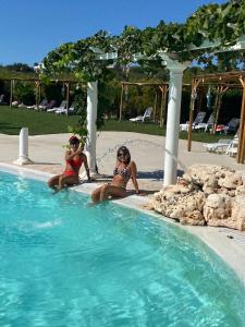 two women are sitting in a swimming pool at All`Ombra del Carrubo in Polignano a Mare +39 photos