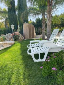 a row of white lounge chairs in a yard at All`Ombra del Carrubo in Polignano a Mare