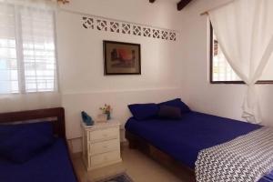 sypialnia z 2 łóżkami z niebieską pościelą i oknem w obiekcie Casa Albatros (Playa-Esmeraldas) w mieście Tonsupa