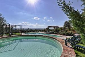 una piscina en un patio con sillas y sol en Poggio Martino, en Cignano