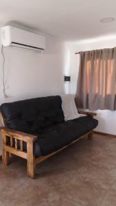 Sofá negro en una habitación con ventana en Cabañas Iñ Püñen, en General Belgrano