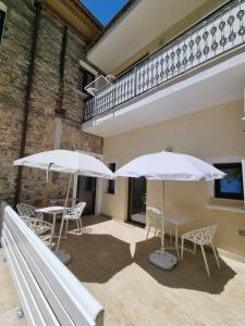 - deux tables et chaises blanches avec parasols sur la terrasse dans l'établissement La Casa di Antonio Rooms, à Palinuro