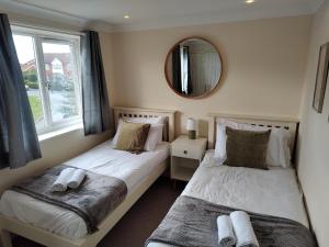 Duas camas num quarto com um espelho. em Wentworth Drive Contractor and family 3 bed Home Grantham em Lincolnshire