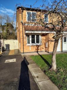 uma casa de tijolos com uma árvore em frente em Wentworth Drive Contractor and family 3 bed Home Grantham em Lincolnshire