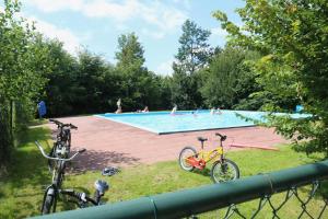 una piscina con due biciclette parcheggiate nell'erba di Glamping Safarilodge 'Grutte Fiif' met airco, extra keuken op veranda en privé achtertuin a Grou