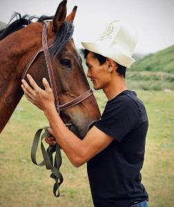 a man in a cowboy hat standing next to a horse at Гостевой дом Темирлан in Kegeti