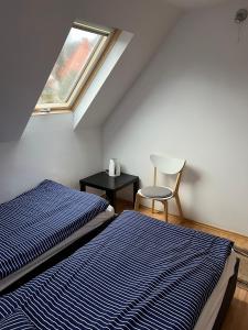two beds in a room with a window and a chair at Noclegi u Emilii in Sopot