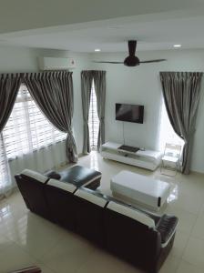 a living room with a couch and a flat screen tv at HK68 Desaru homestay in Kangkar Chemaran