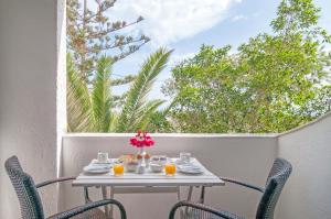 a table on a balcony with a table and chairs at Holiday Beach Resort Santorini in Perivolos