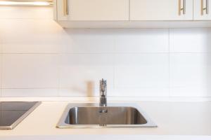 a stainless steel sink in a kitchen with white cabinets at LU&CIA Victoria 4 in Málaga