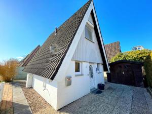 una casa blanca con techo de gambrel y entrada en Familienfreundliches Ferienhaus in 5 min zum Strand mit Terrasse und kostenlosem Parkplatz, en Cuxhaven