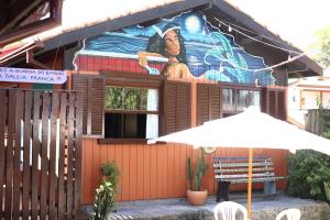 a building with a painting on the side of it with an umbrella at Hostel Antônio Pescador Guarda do Embau in Guarda do Embaú