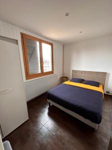 een slaapkamer met een bed en een raam bij Place Royale pour 10 à 12 personnes à 30 mèt des pistes de Ski et Vtt in Métabief