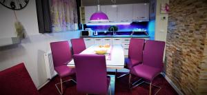 une cuisine avec une table blanche et des chaises violettes dans l'établissement Apartmani Peyton, à Slavonski Brod