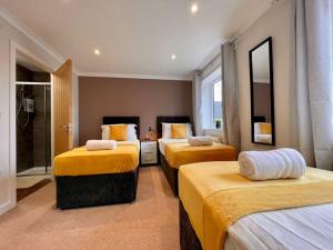 a hotel room with three beds with yellow sheets at Big Modern House - 15min to NEC - Sleeps 10 in Birmingham