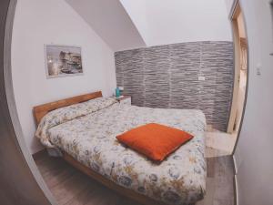 Schlafzimmer mit einem Bett mit orangefarbenem Kissen in der Unterkunft Casa vacanza Terra Mare in Castellammare del Golfo