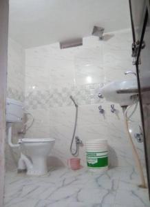a white bathroom with a toilet and a sink at Kalawati Niwas in Bodh Gaya